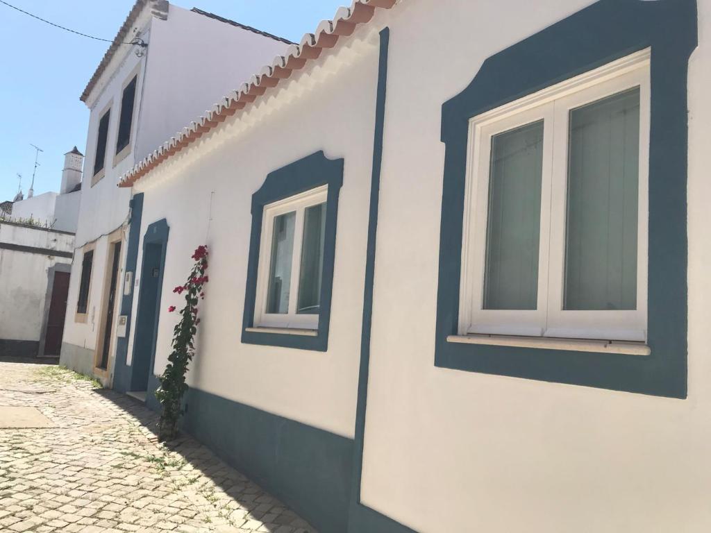 - un bâtiment blanc et bleu avec des fenêtres donnant sur une rue dans l'établissement Casa 16, à Tavira