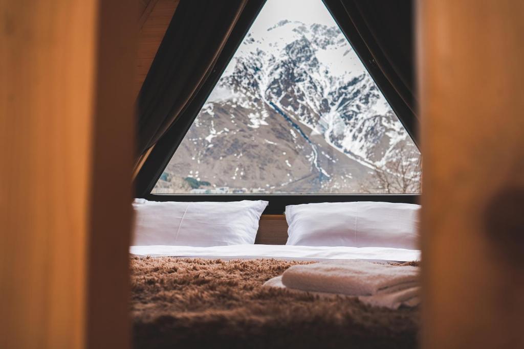 a bed in a room with a view of a mountain at Cottages LIZA in Stepantsminda