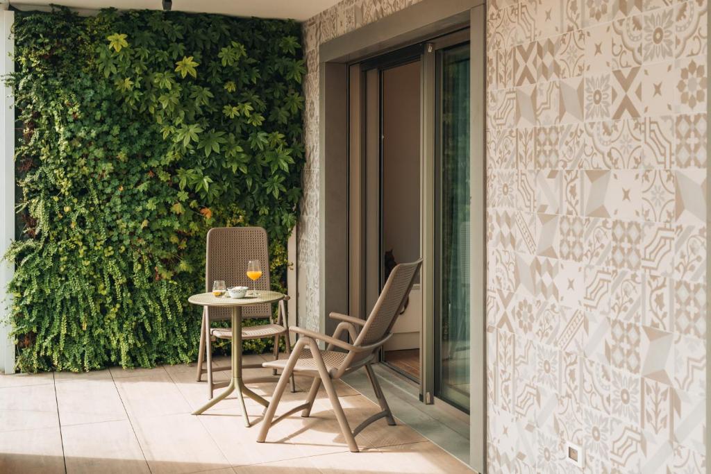 a table and chairs on a patio with a green wall at Sea Breeze in Caorle