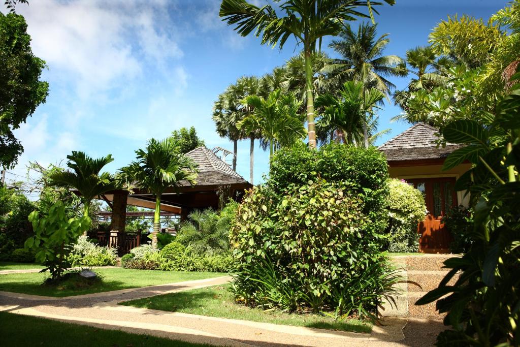ein Haus mit Palmen davor in der Unterkunft Pai Tan Villas - SHA Extra Plus in Strand Bang Tao
