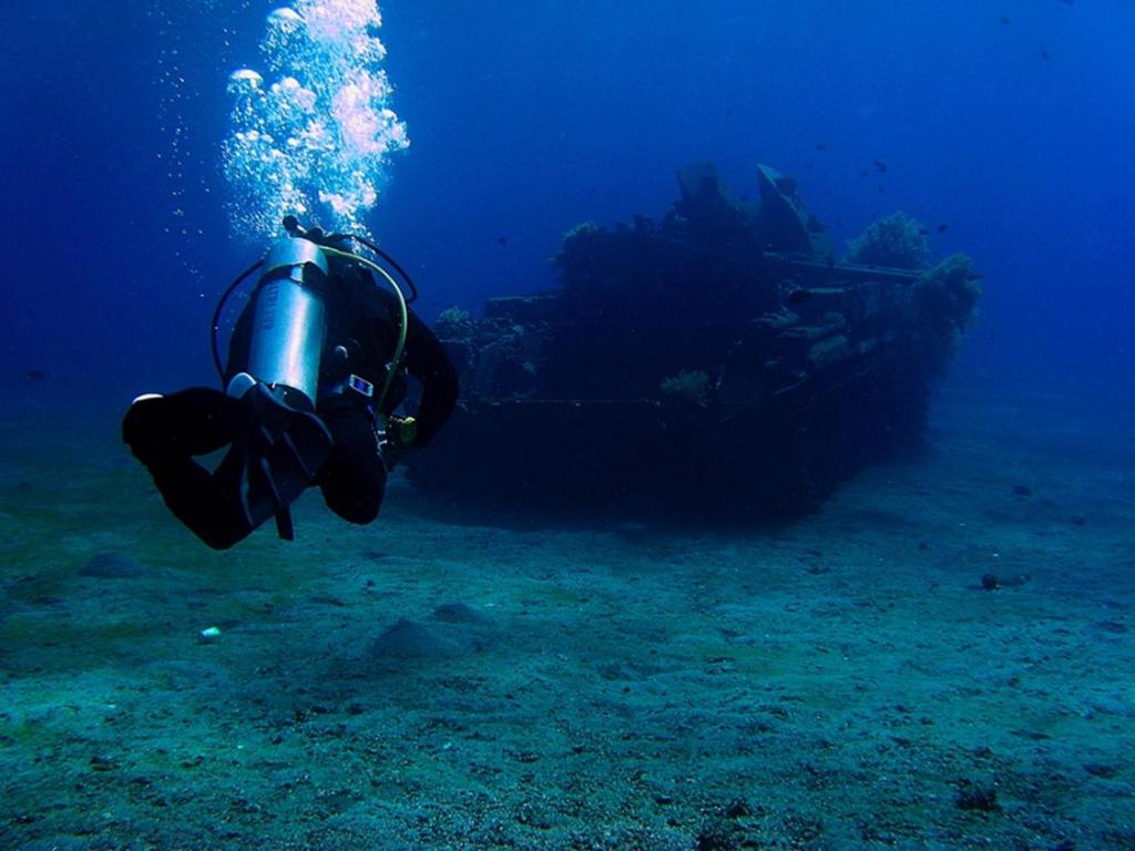a person swimming in the ocean next to a boat at Arab Divers Dive Center and Bed & Breakfast in Aqaba