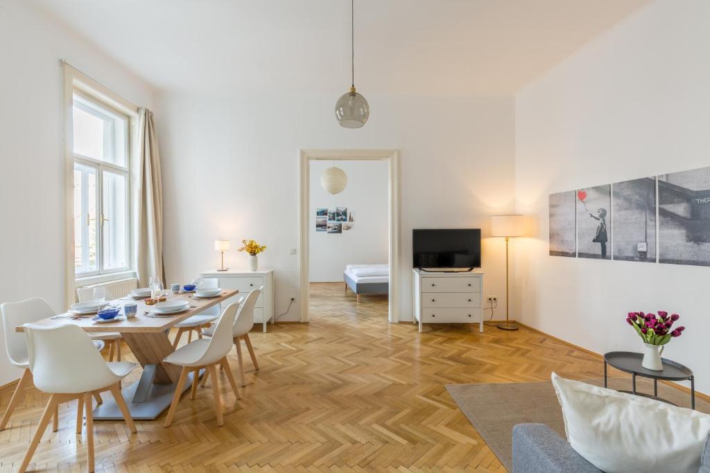 ein Wohnzimmer mit Tisch und Stühlen und einem Fernseher in der Unterkunft Grand Viennese Residence in Wien