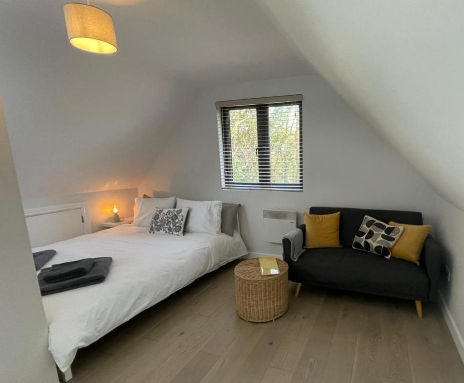 1 dormitorio con 1 cama y 1 sofá en The Annexe - woodland views and close to beach! en Barton on Sea