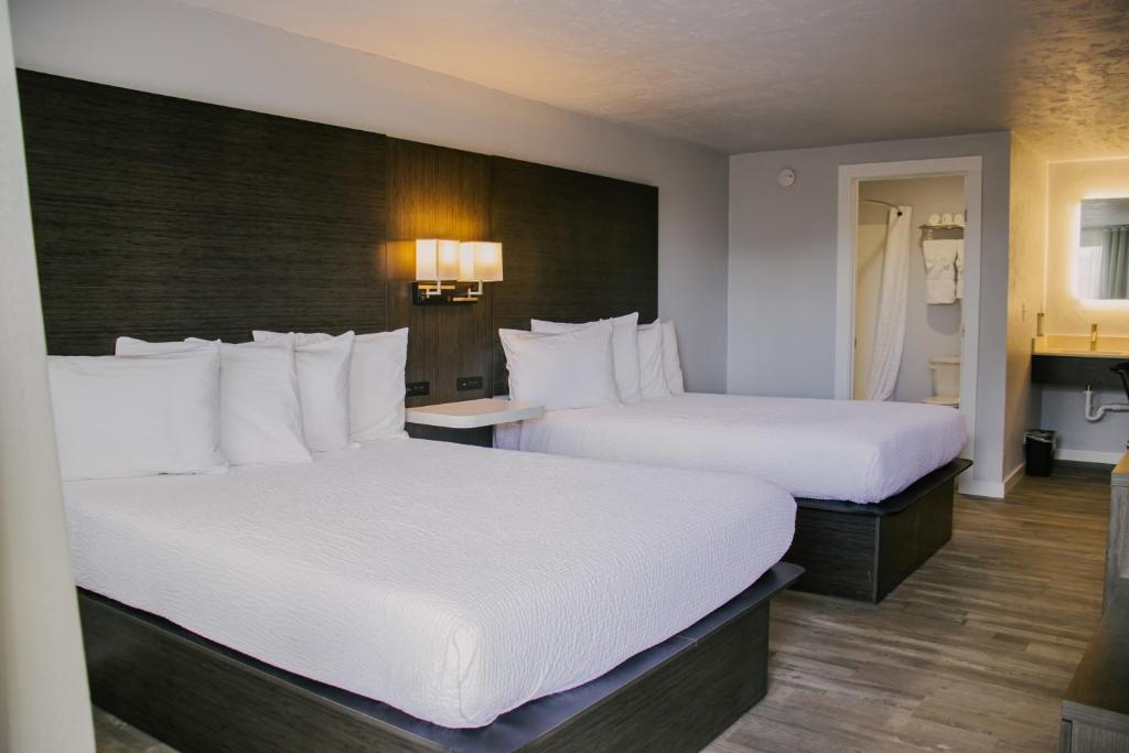duas camas num quarto de hotel com lençóis brancos em Bears Ears Inn em Blanding
