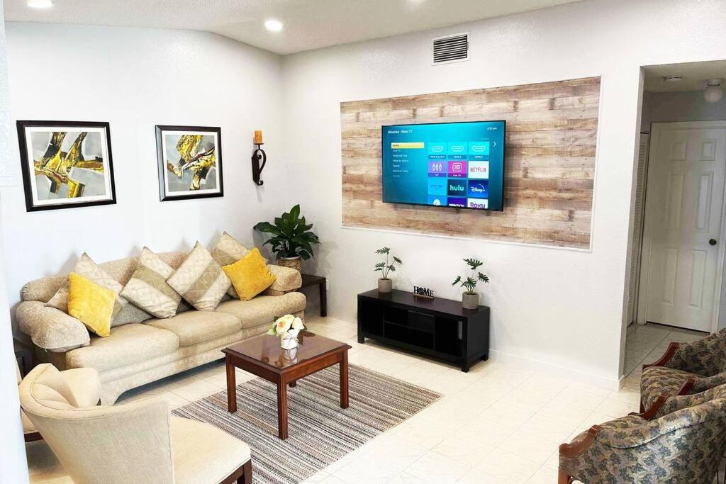 uma sala de estar com um sofá e uma televisão na parede em Amazing & cozy Duplex near Zoo Miami ! em Miami