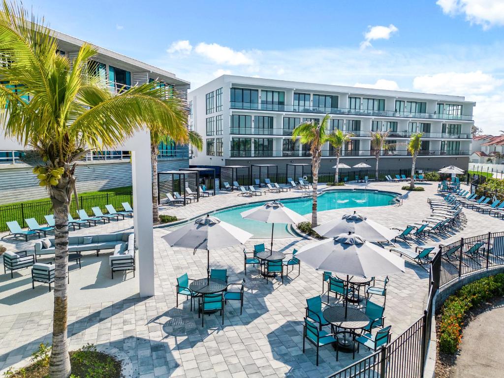 an outdoor pool with tables and chairs and a building at Villatel at Harbor Island Beach Club in Melbourne Beach