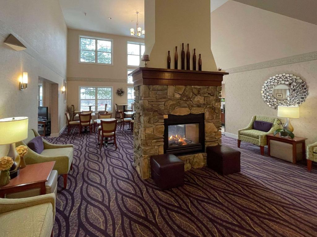 a living room with a fireplace in a hotel room at Smart Suites, Ascend Hotel Collection in Burlington