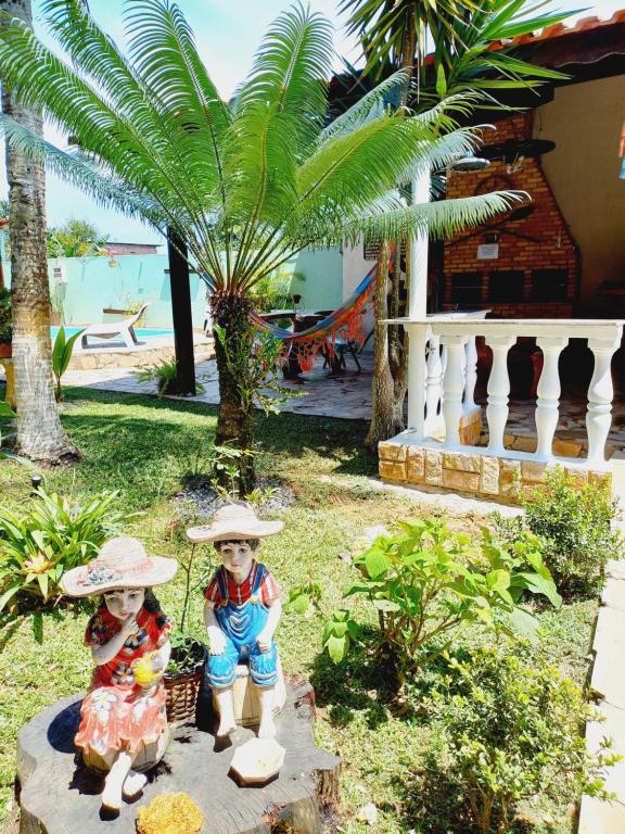 two children wearing hats standing in a yard with a palm tree at Chalé da Ju in Ubatuba
