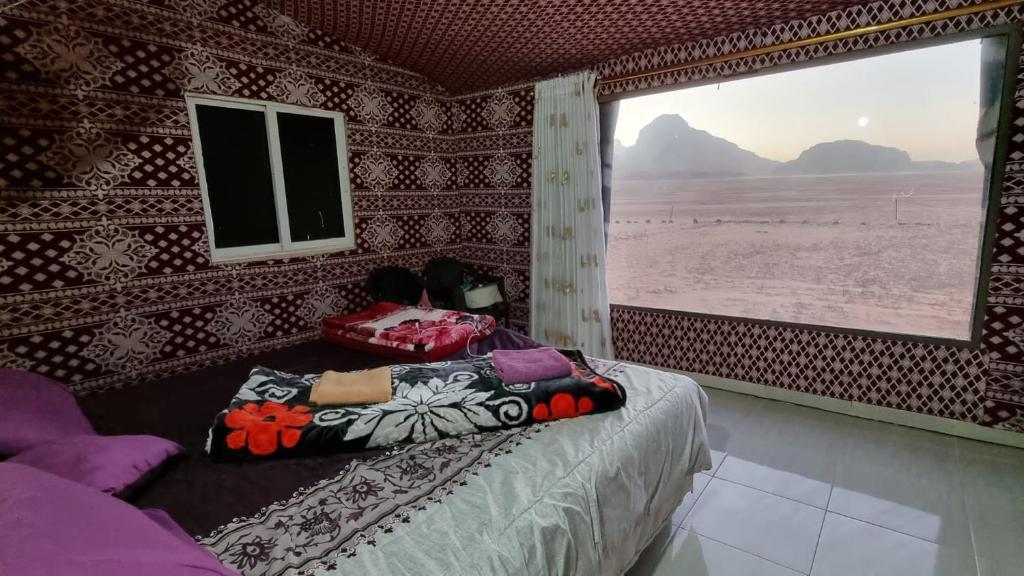 a bedroom with a bed with a view of the desert at Qais Camp Wadi Rum in Wadi Rum