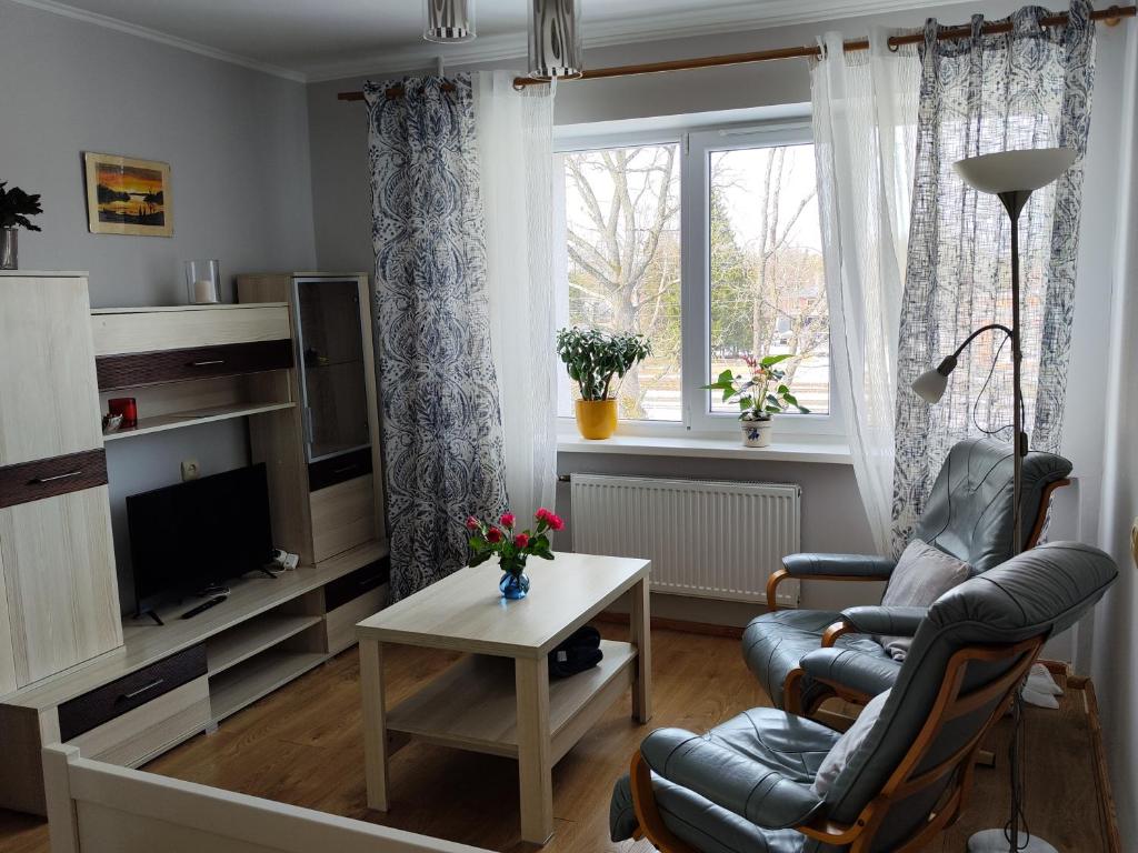 a living room with a chair and a table and a tv at Station street apartments in Sigulda