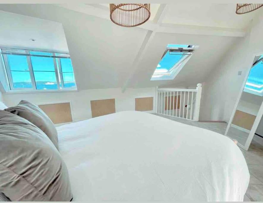 a bedroom with a white bed in a room with windows at The View, Kingsand, luxurious seafront penthouse apartment with sun trap balcony and incredible sea views in Kingsand