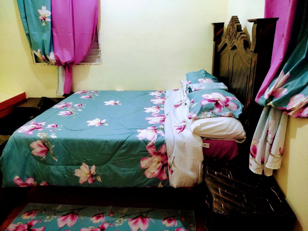 a bed with a green comforter with flowers on it at Casa Yudy in Santa Bárbara de Samaná