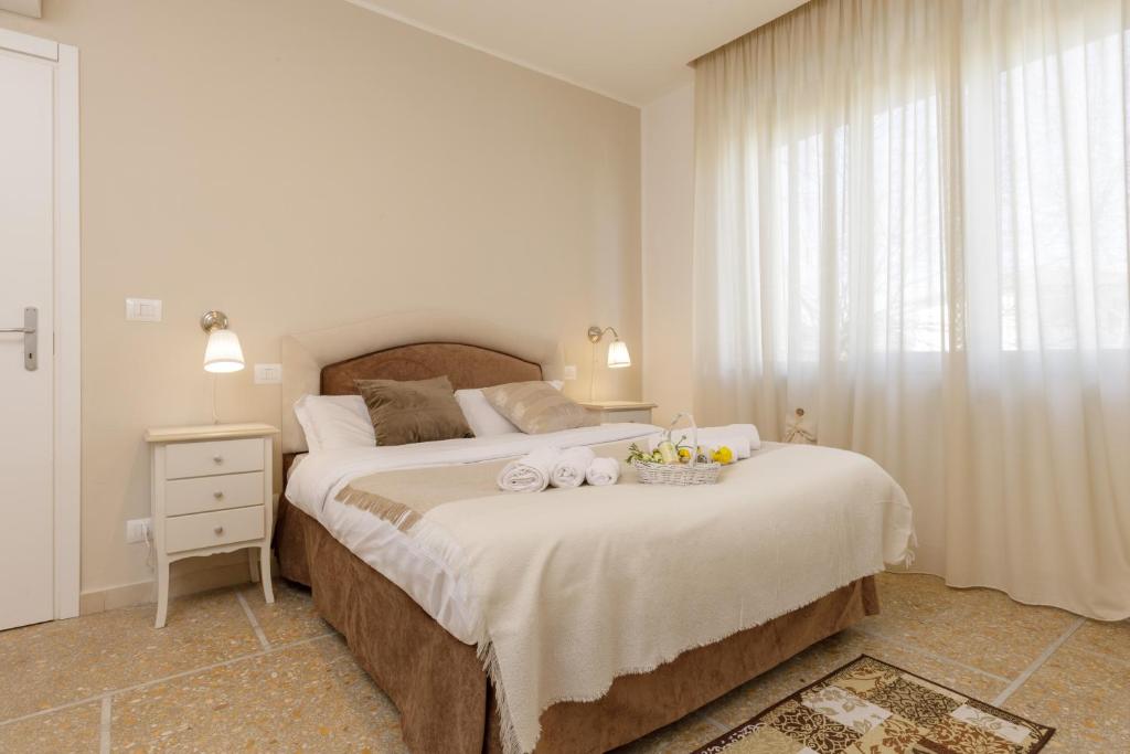 a white bedroom with a large bed and a window at Da Rita Affittacamere in Pisa