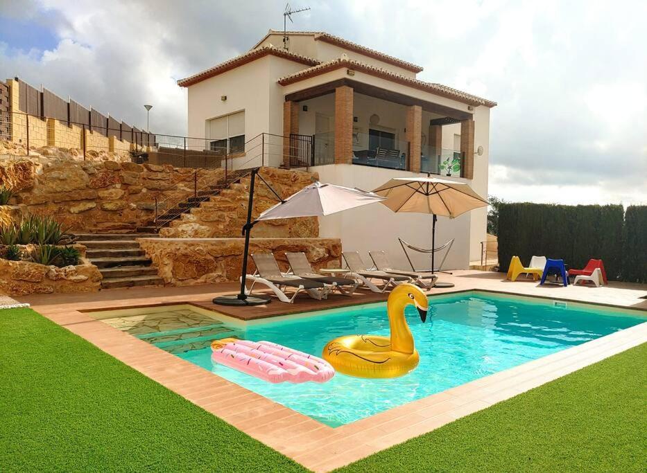 a swimming pool with a swan in front of a house at Villa al vent (lujo & relax) in Benitachell