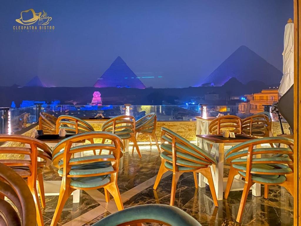 um grupo de cadeiras e uma mesa com vista para as pirâmides em Cleopatra Pyramids View no Cairo