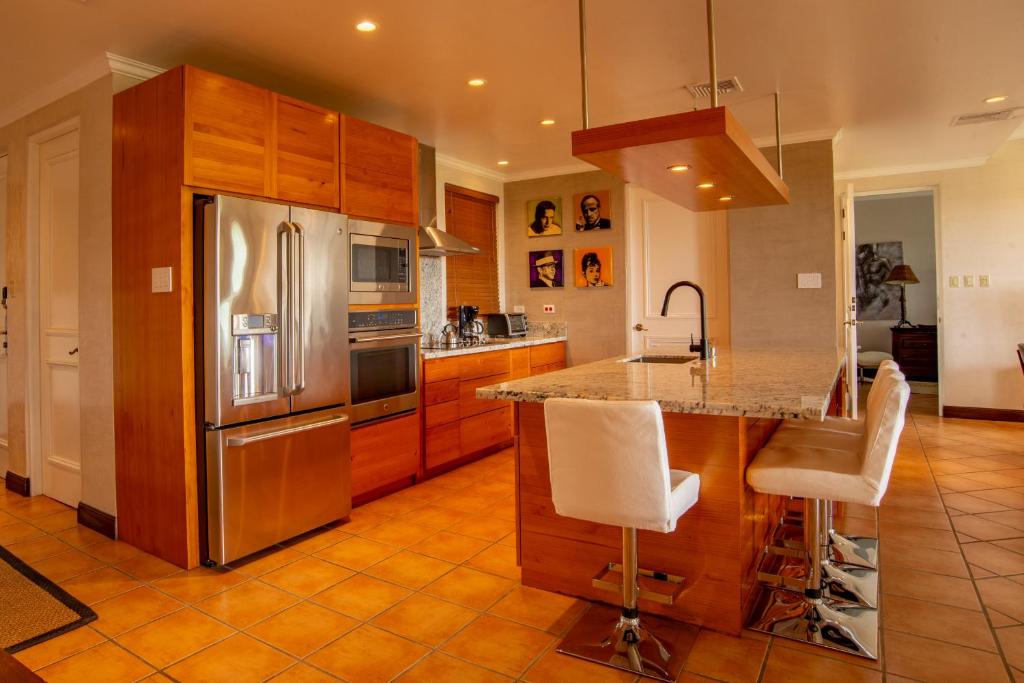 a kitchen with wooden cabinets and a stainless steel refrigerator at Bougainvillea 8211 Luxury Apartment - Reserva Conchal in Playa Conchal