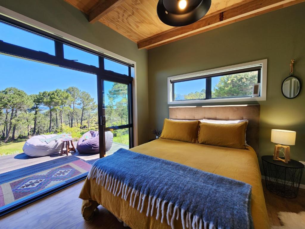 a bedroom with a bed and a large window at Hahei Hideout Retreat in Hahei