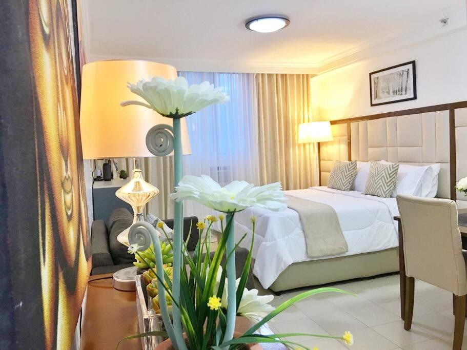 a hotel room with a bed and a table with flowers at Attractive studio with Luxury bed Good for 1-4pax High speed WiFi with Netflix Free Pool & Parking in Suba