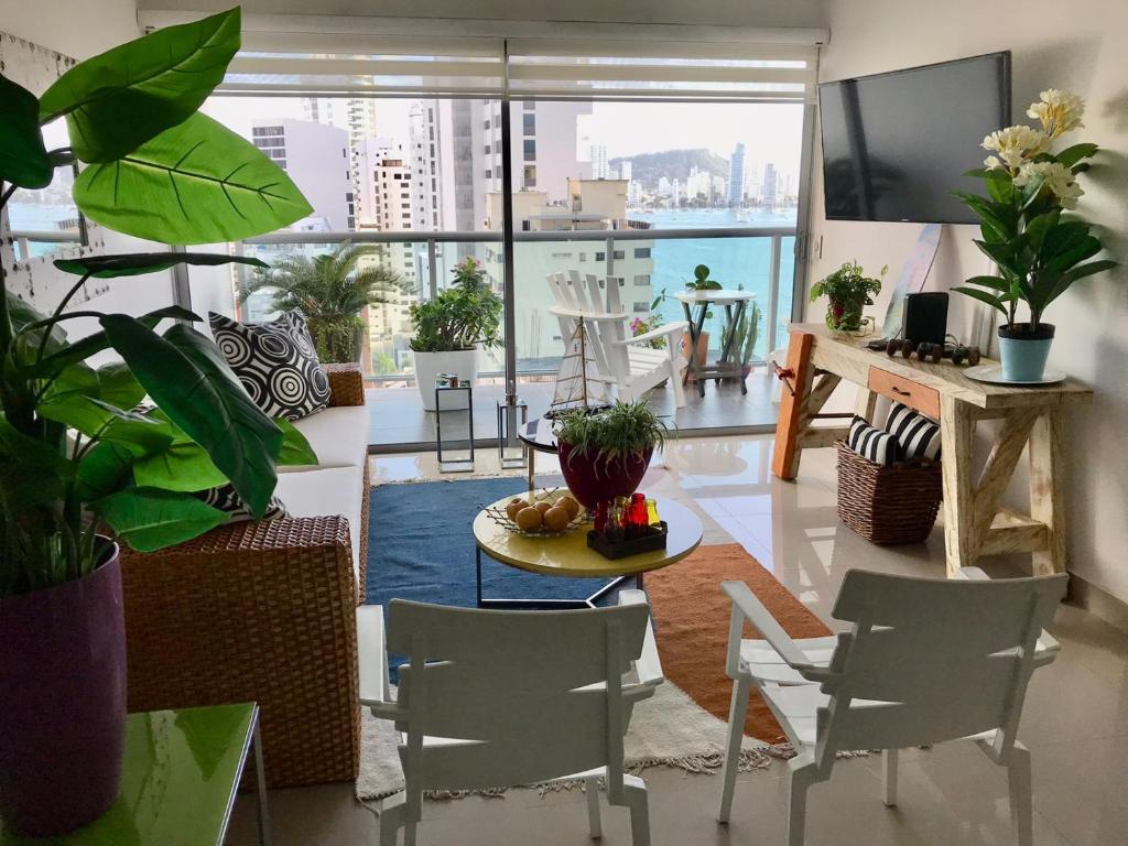 een woonkamer met een tafel en stoelen en een groot raam bij Acogedor y lujoso apartamento en edificio infinitum in Cartagena