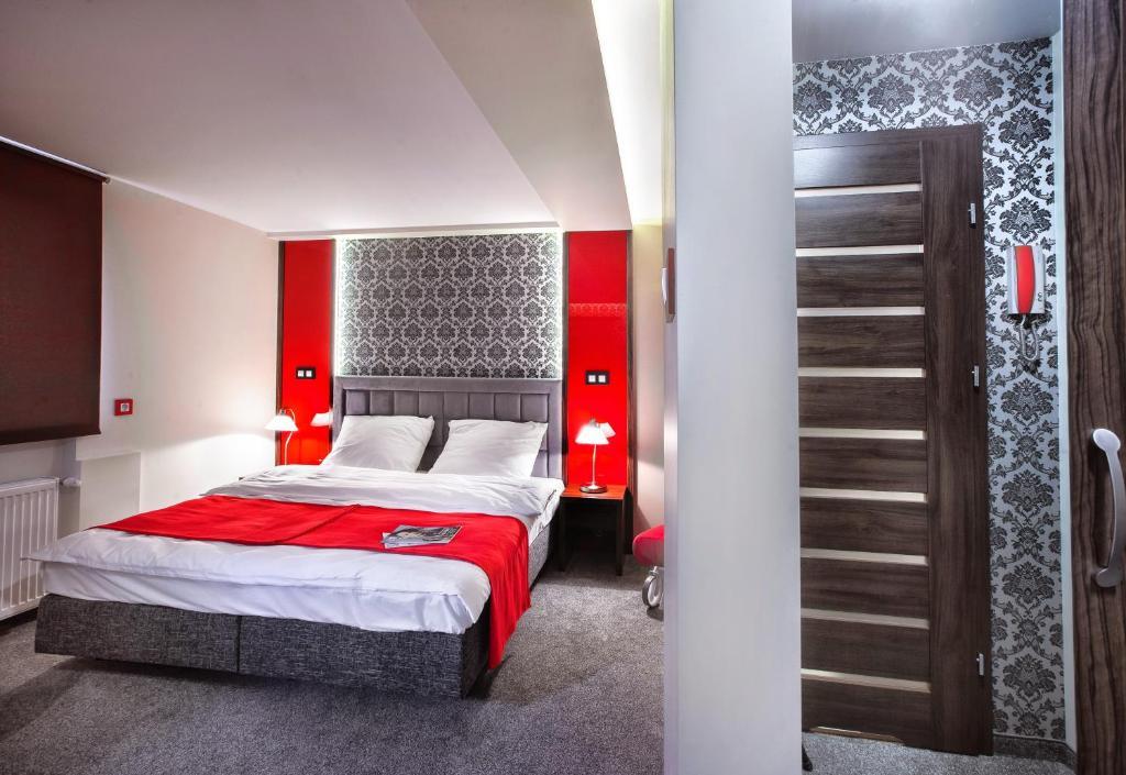 a bedroom with a bed with a red wall at Apartament Podwale in Łańcut