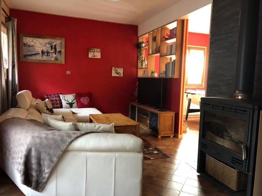 ein Wohnzimmer mit einem weißen Sofa und einer roten Wand in der Unterkunft La Maison de Suzanne in Murol