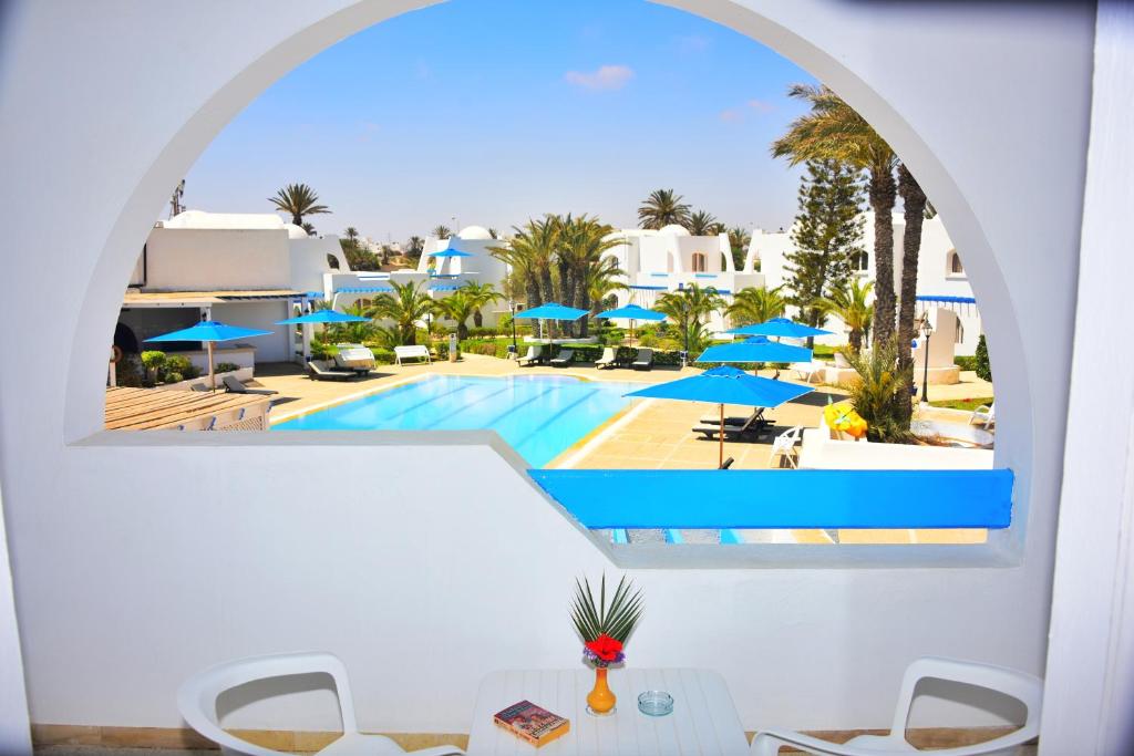 Blick auf den Pool aus dem Fenster eines Resorts in der Unterkunft Zenon Djerba in Midoun