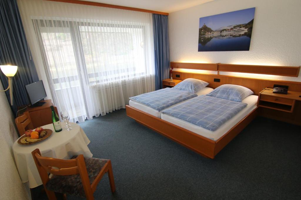 ein Schlafzimmer mit einem Bett, einem Tisch und einem Stuhl in der Unterkunft Hotel Klasen in Cochem