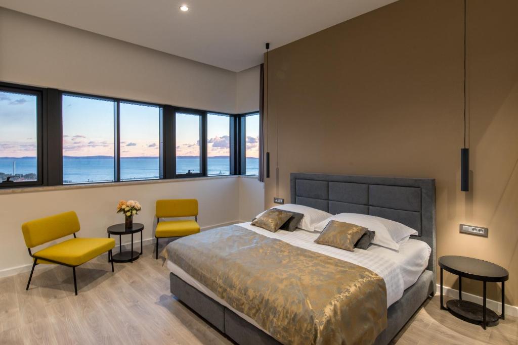 1 dormitorio con 1 cama, 2 sillas y ventanas en Seascape Luxury Rooms, en Split