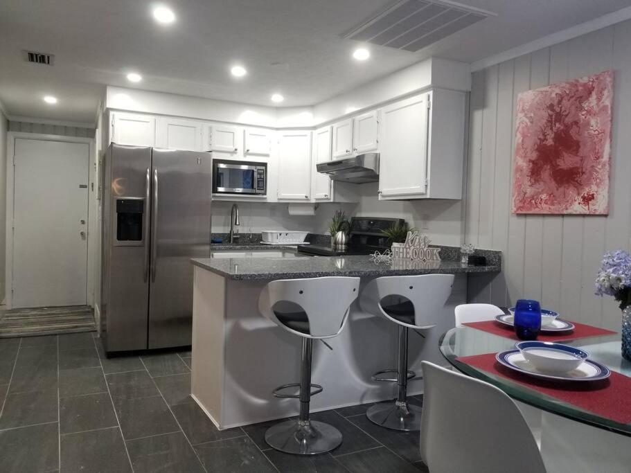 a kitchen with white cabinets and a stainless steel refrigerator at Beautiful cottage near Lake Louisa & mins from Disney, Vehicle Rental Available in Clermont