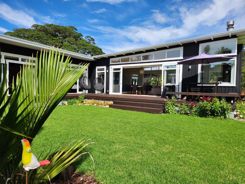 a house with a yard with a bird on the lawn at Hot Water Beach Escape in Hotwater Beach