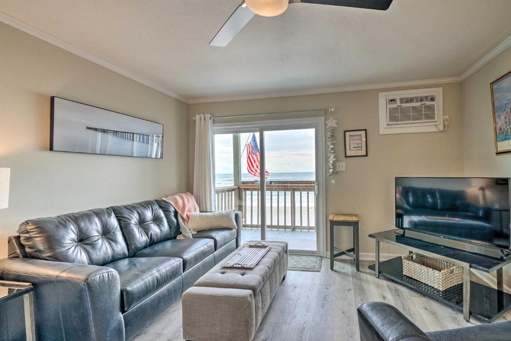 a living room with a leather couch and a flat screen tv at Chic Oceanfront North Topsail Beach Condo with Deck in North Topsail Beach