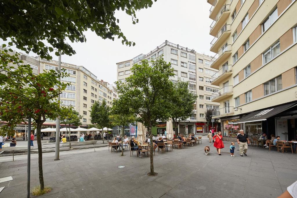 une rue urbaine avec des gens, des tables et des bâtiments dans l'établissement Vut Salvador Santiago, à Saint-Jacques-de-Compostelle