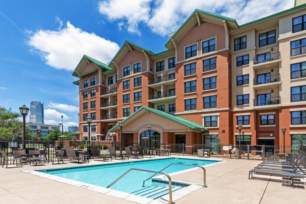 Residence Inn by Marriott Oklahoma City Downtown/Bricktown في مدينة اوكلاهوما: مسبح امام مبنى به طاولات وكراسي