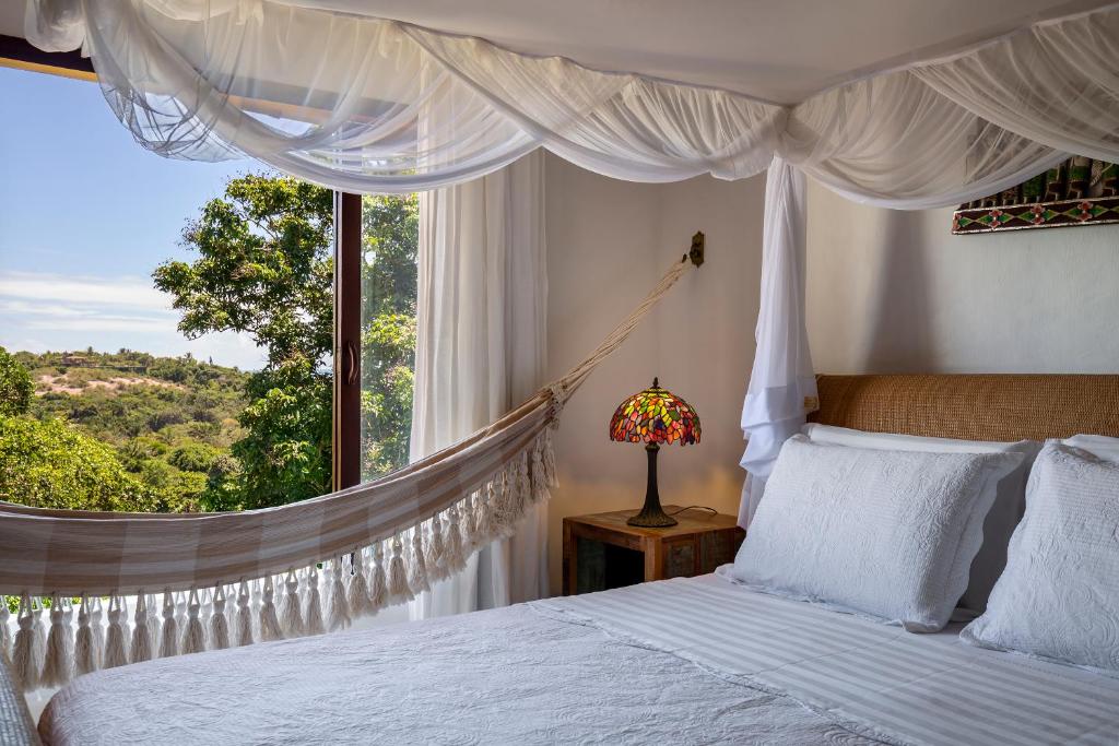 um quarto com uma cama com rede de descanso em frente a uma janela em Pousada Hospedaria do Quadrado em Trancoso