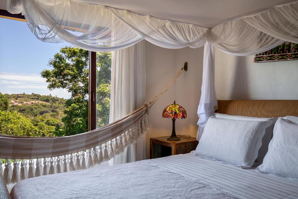 a bedroom with a bed with a hammock in front of a window at Pousada Hospedaria do Quadrado in Trancoso