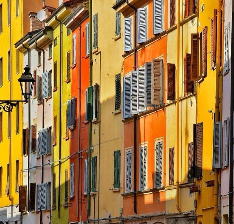 um grupo de edifícios com persianas coloridas sobre eles em Jolie Maison au coeur de Parma Parking privé gratuit em Parma