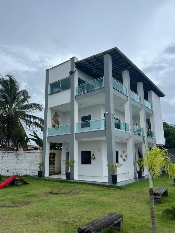 圣阿马鲁Eco House Gaivota - Cond Ville Portal das Dunas的一栋白色建筑，前面有一棵棕榈树