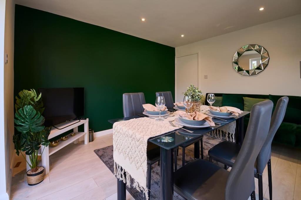 ロンドンにあるFabulous 3 bed NW London apartment with private gardenの緑の壁のダイニングルーム(テーブル付)