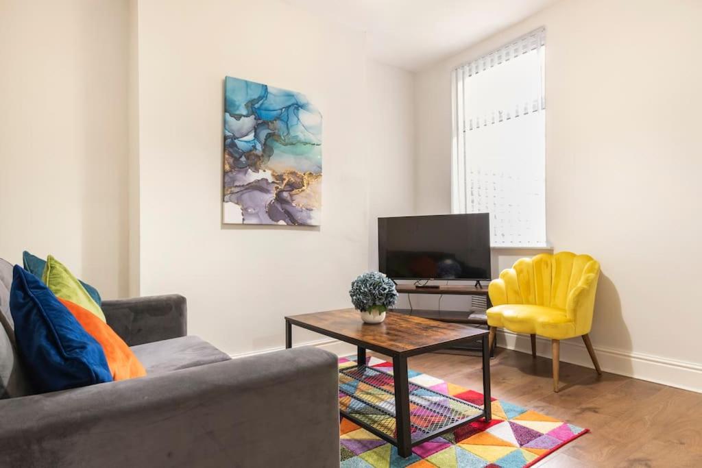 ein Wohnzimmer mit einem Sofa, einem Tisch und einem TV in der Unterkunft 3-bedroom Home in Liverpool L15 with FREE Parking in Liverpool