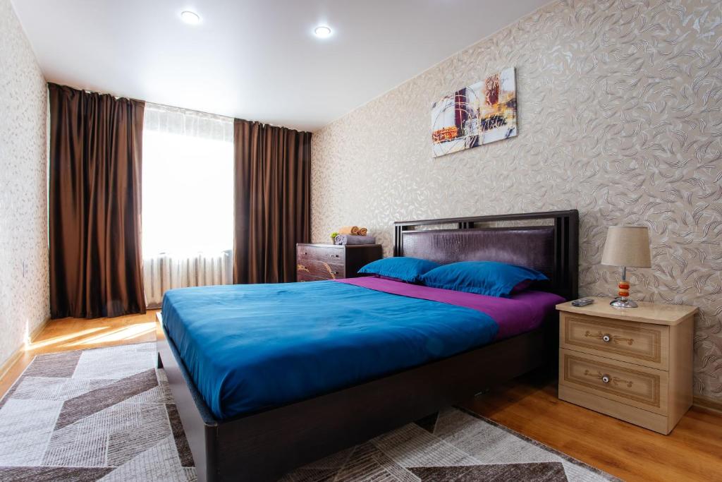 Un dormitorio con una cama azul y una ventana en 1 комнатная квартира в центре на Пушкина 92 en Kostanái