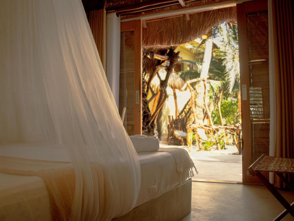 uma cama com um véu num quarto com uma janela em Cabañas Playa Condesa em Tulum