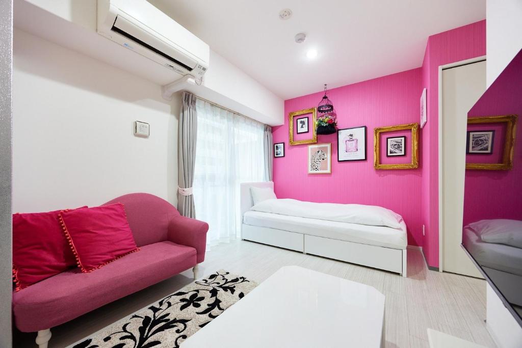 uma sala de estar com paredes cor-de-rosa e um sofá em MONTANA FLAT YEBISU - Vacation STAY 9873 em Osaka