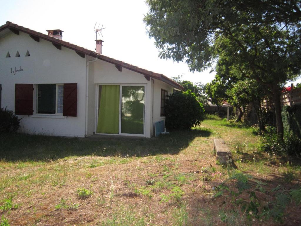 une maison blanche avec une porte verte dans la cour dans l'établissement Maison T2 avec jardin clos, proche commerces et mer - 4 personnes - Biscarrosse Plage - FR-1-521-66, à Biscarrosse-Plage