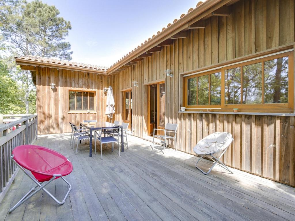 une terrasse en bois avec une table et des chaises dessus dans l'établissement Belle villa en bois 6 personnes avec terrasse et Wi-Fi à Biscarrosse - FR-1-521-71, à Biscarrosse