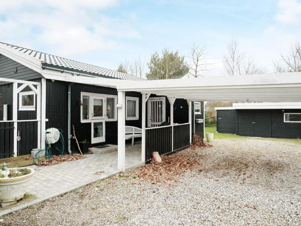 ein schwarzes Haus mit einem weißen Dach und einer Terrasse in der Unterkunft Holiday home Gilleleje XCV in Gilleleje