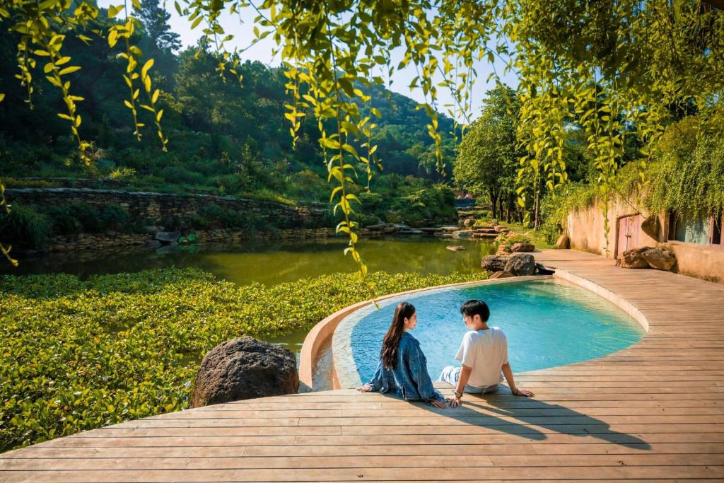 a man and a woman sitting next to a swimming pool at Amaya Retreat in Sóc Sơn