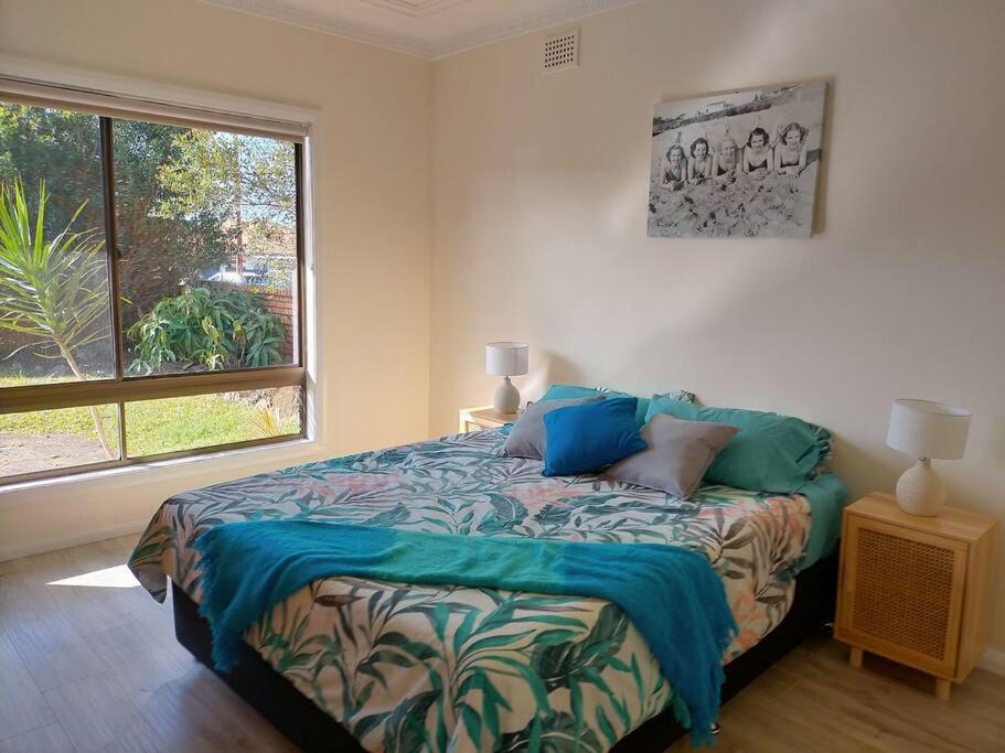 a bedroom with a bed and a large window at Boyle's Beach House - Fully furnished 3 Bedroom home. Secure parking. in Nambucca Heads