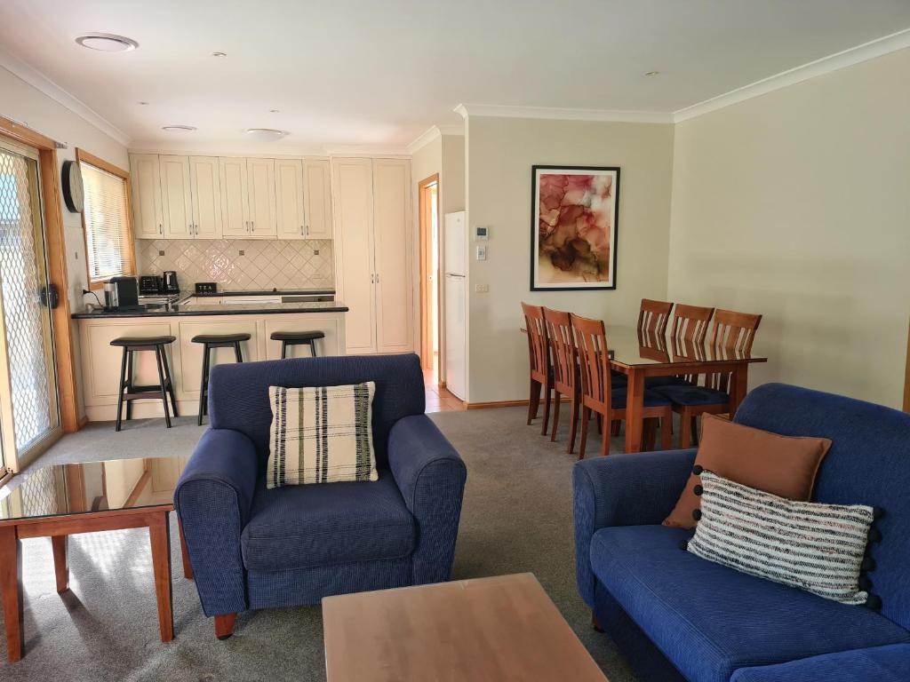 uma sala de estar com duas cadeiras azuis e uma cozinha em DELANY VILLAS BRIGHT - Spa luxury on Delany Avenue em Bright
