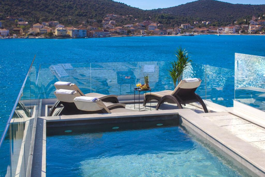 a swimming pool with chairs and a view of the water at Villa Lux in Vinišće