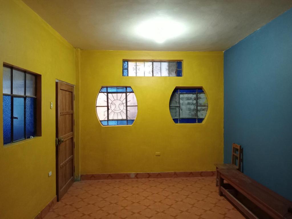 a room with three windows and a yellow wall at Casa Huamanga in Ayacucho